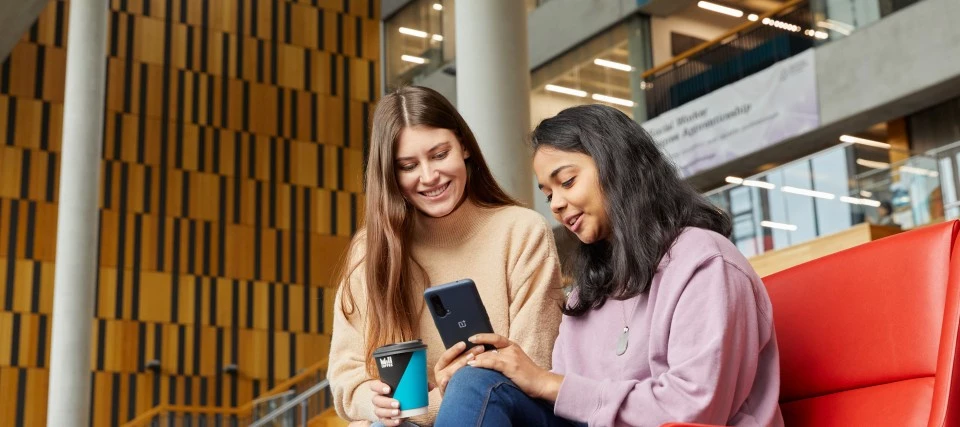 Two people sitting and looking at phones